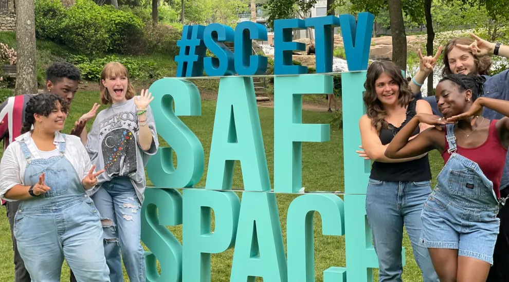 group photo of safe space teens around a sign reading safe space