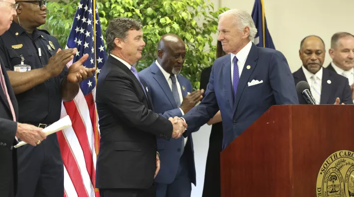 South Carolina Department of Corrections Director Bryan Stirling, left, shakes hands with Gov. Henry McMaster, right, after Stirling announces the state has the lowest recidivism rate in the country at under 22% at a ceremony on Tuesday, July 13, 2021, at the Manning Reentry / Work Release Center in Columbia, South Carolina. In the past 10 years the rate has fallen more than 10 percentage points. (AP Photo/Jeffrey Collins)