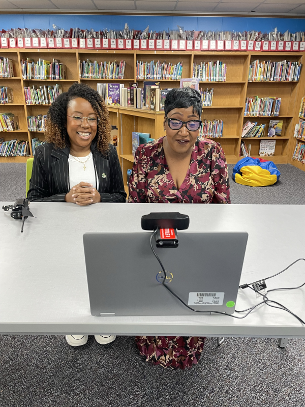 photo of Raven Favor and W.S. Sandel Elementary Principal Claudia Brooks-McCallum sitting in the school library