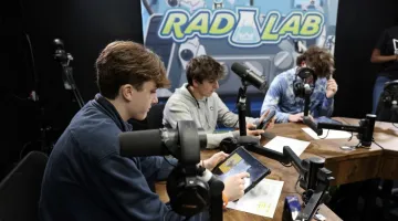 photo of students playing Skillionaires game in front of Rad Lab poster backdrop