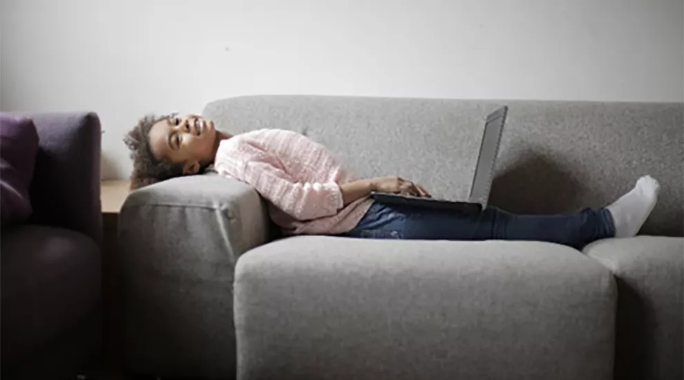 Student on sofa with laptop smiling