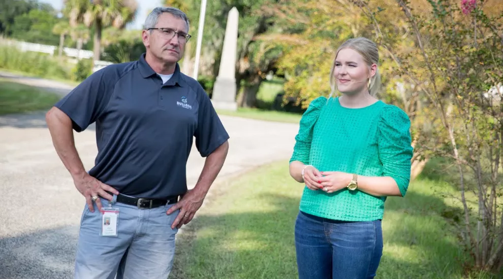 Devyn stands next to a male tour guide in a cemetery.