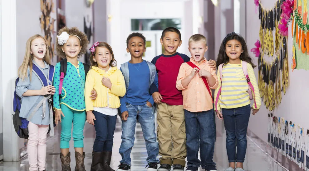 photo of several early-ed students standing with backpacks on in a school hallway