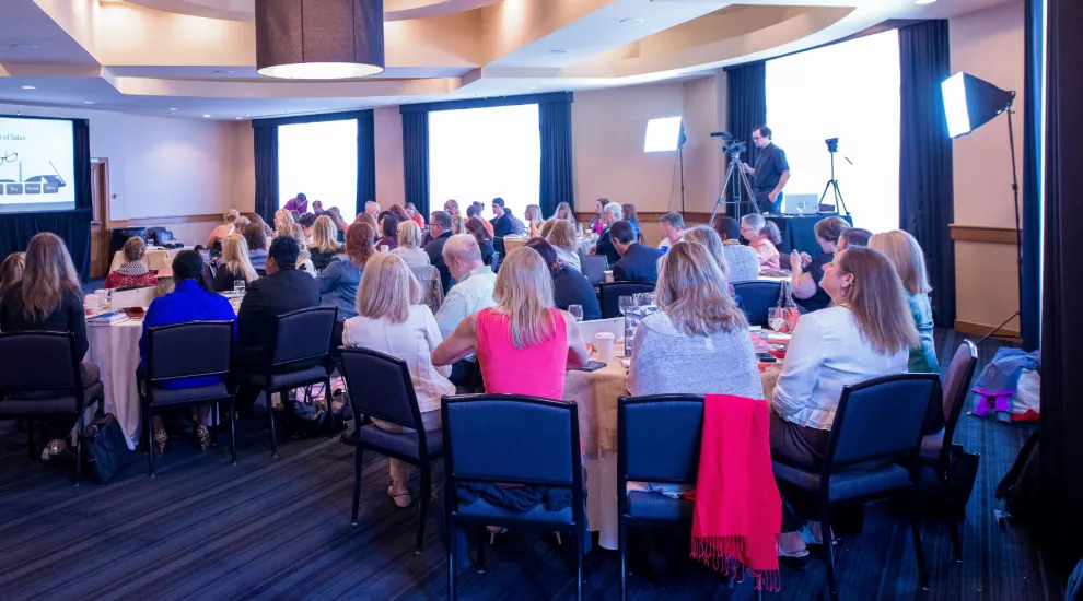 photo of people at tables watching a presentation