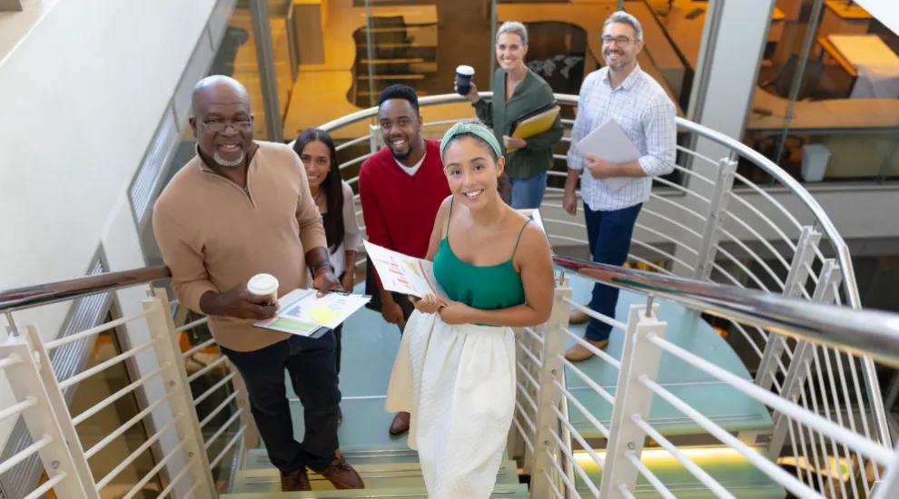 photo of several people going up stairs, some holding coffee and/or papers 