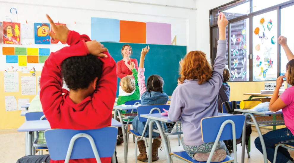 photo of teacher standing in front of elementary school students in a classroom