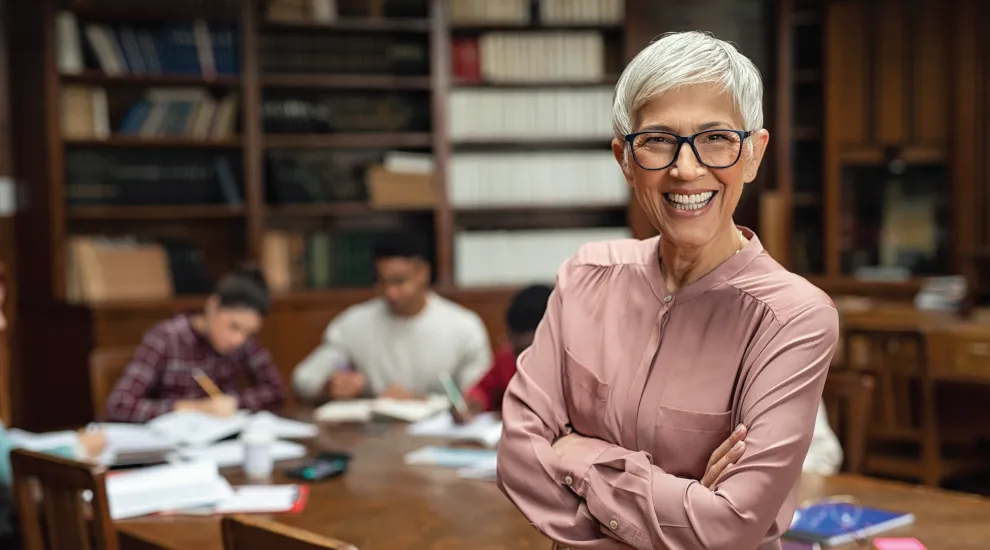 photo of smiling woman educator in front of 4 students working at a table