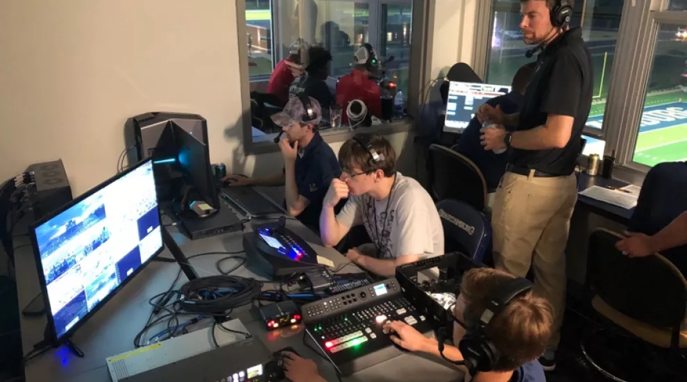 students and supervisor in broadcast control booth