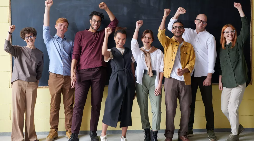 photo of several colleagues holding their hands up in triumph