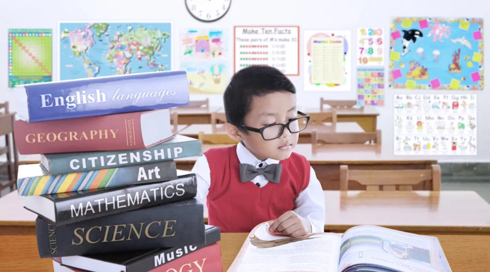 elementary student with a stack of subject books