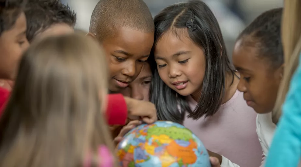 several children looking at a globe