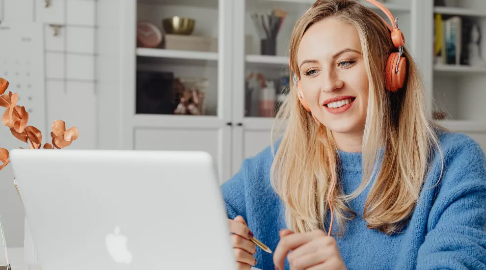 photo of woman looking at laptop screen and wearing headphones