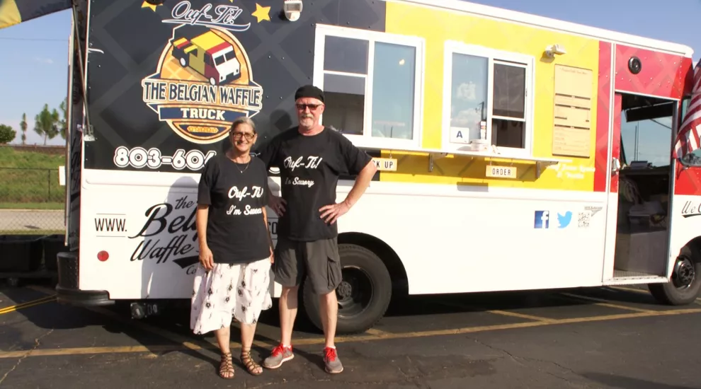Owners of The Belgian Waffle Truck standing in front of their food truck.