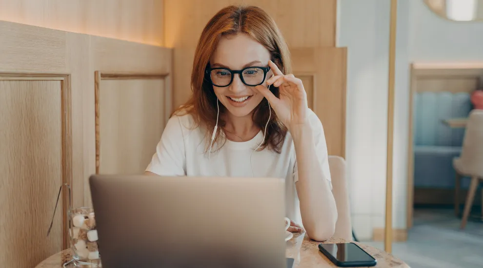 photo of a woman sitting inside a cafe looking at a laptop screen