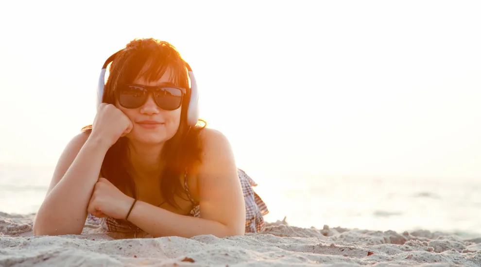 photo of woman on beach with headphones on