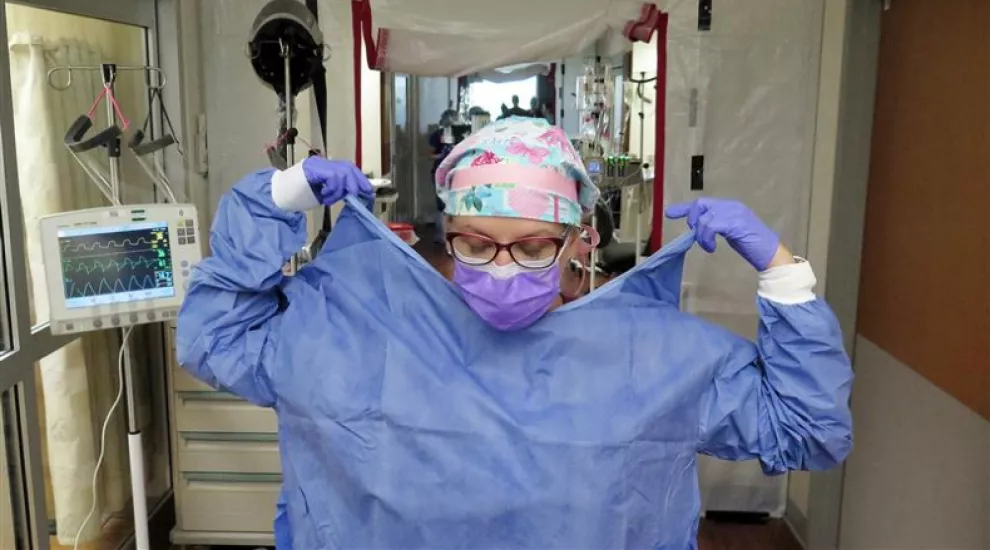 Critical care nurse Michele Baudet gowns up before going into a COVID-19 patient's room 