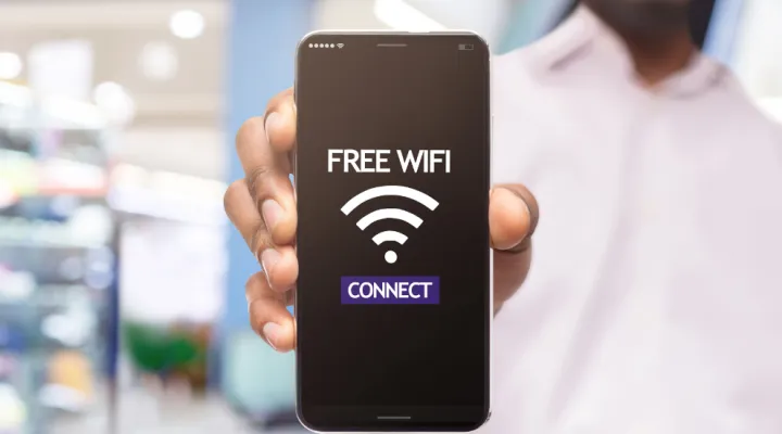 photo of man holding a phone that shows the words "FREE WIFI CONNECT"