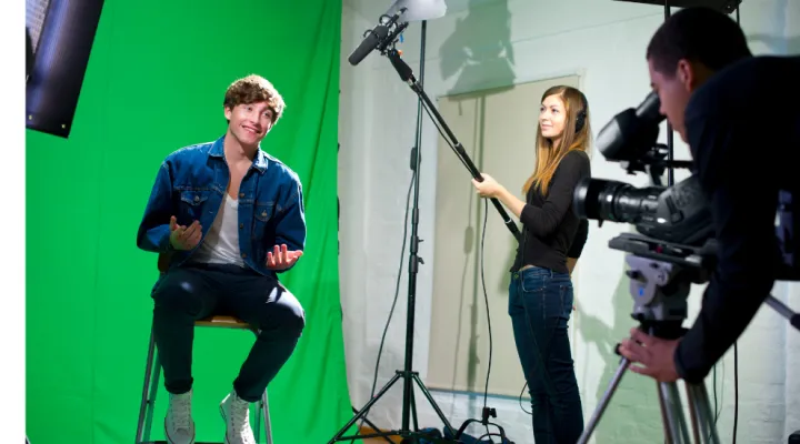 photo of 3 students doing a filming in front of a greenscreen