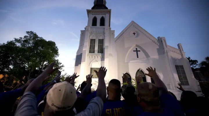 FILE - Members of the Omega Psi Phi Fraternity lead a crowd of people in prayer outside the Emanuel African Methodist Episcopal Church after a memorial for the nine people who were shot and killed during Bible study in Charleston, S.C., Friday, June 19, 2015. When violence comes to a public place, as it does all too often in our era, a delicate question lingers afterward: What should be done with the buildings where blood was shed? (AP Photo/Stephen B. Morton, File)