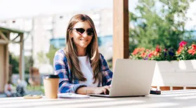 photo of a woman sitting outside wearing a long sleeve shirt and using a laptop